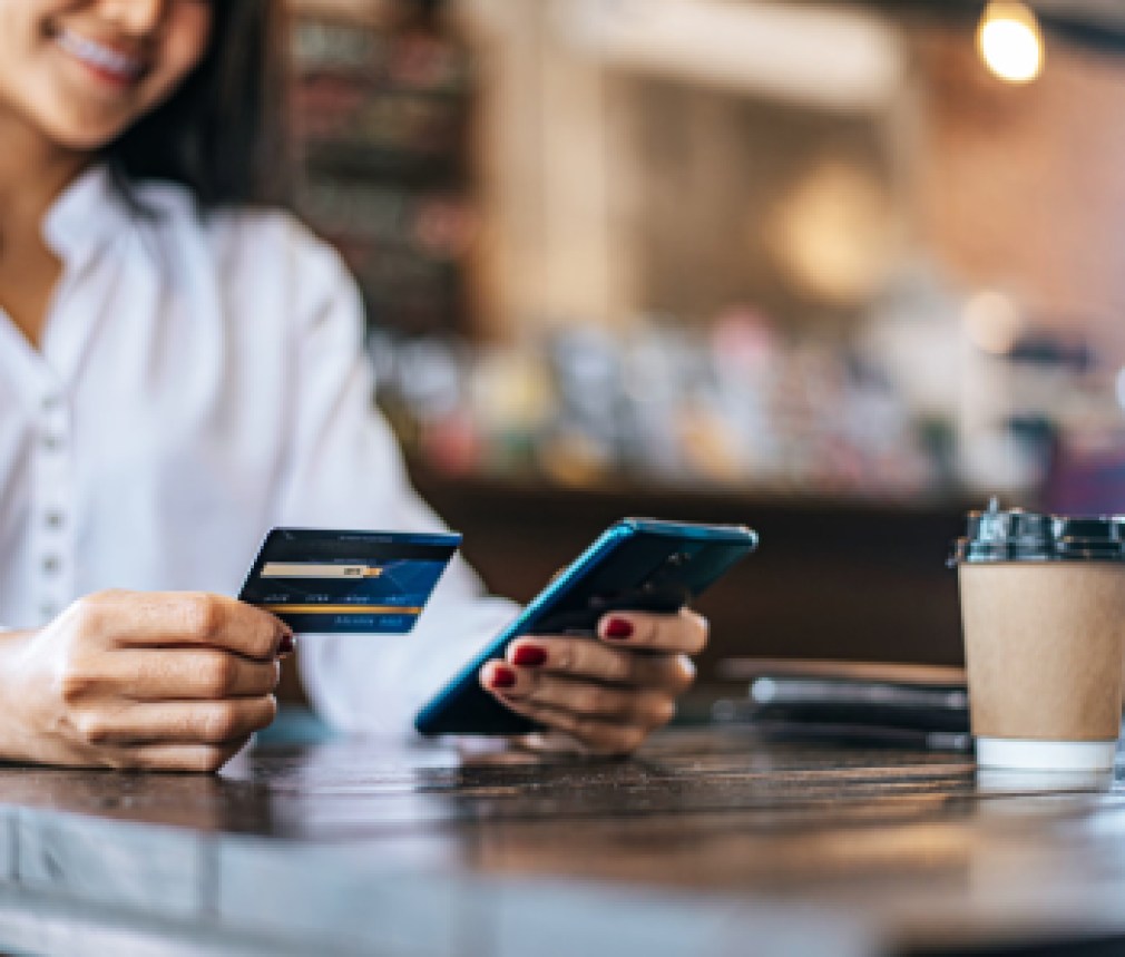 Pay for goods by credit card through a smartphone in a coffee shop.