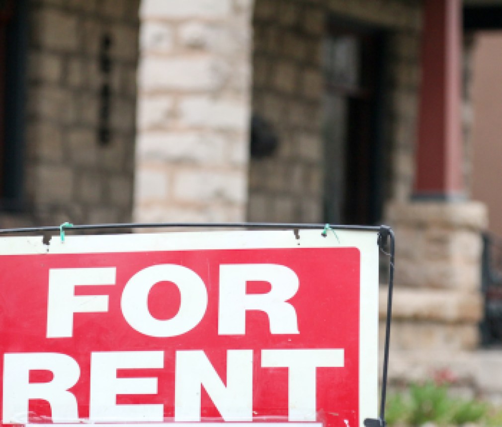 For rent sign posted in front of a blurry front porch