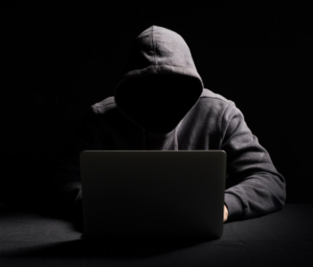 Hacker working on laptop in the dark