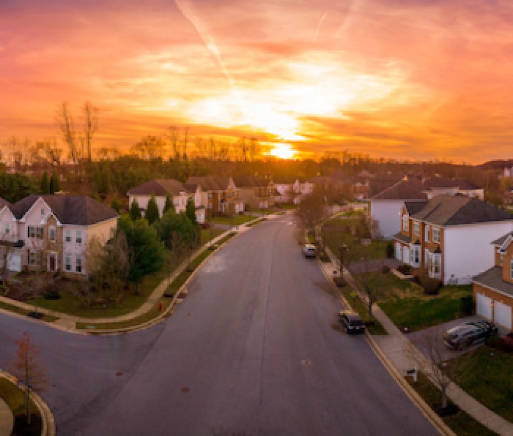Aerial sunset panorama view of luxury upscale residential neighborhood gated community street in Maryland USA, American real estate with single family homes brick facade cul-de-sac (dead-end)
