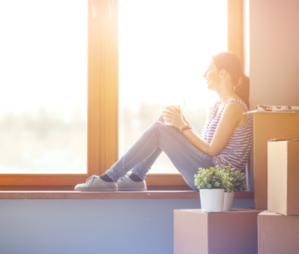 Woman in a new home with cardboard boxes. Woman in the house.