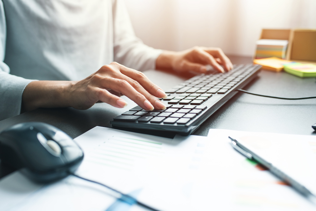 Business woman hand with computer mouse and keyboard on table at office