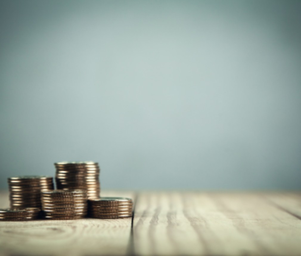 Stack of coins on wooden table.