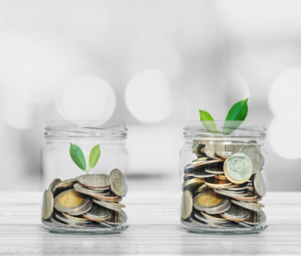 Hand putting coin in glass bottles with plants glowing, Saving money and investment  concepts