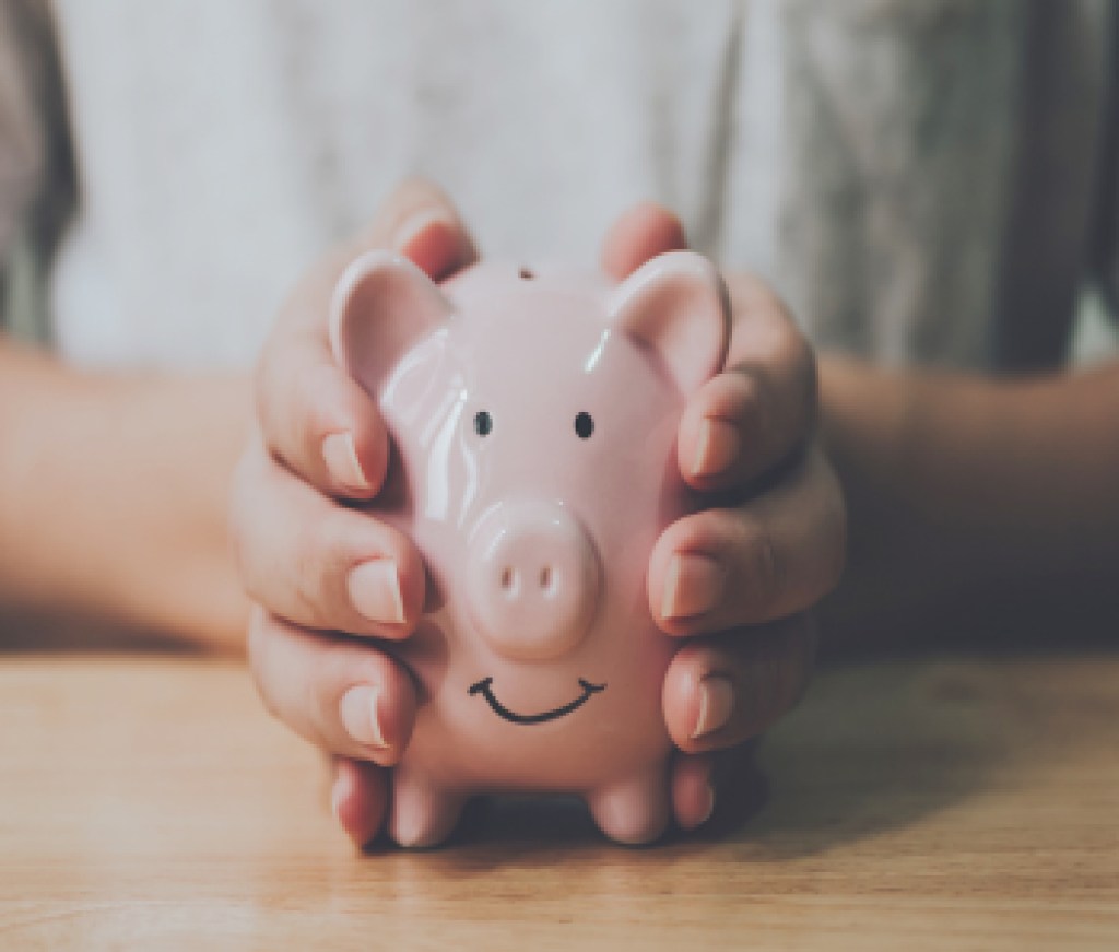 Panoramic image, Man hand holding piggy bank on wood table. Save money and financial investment