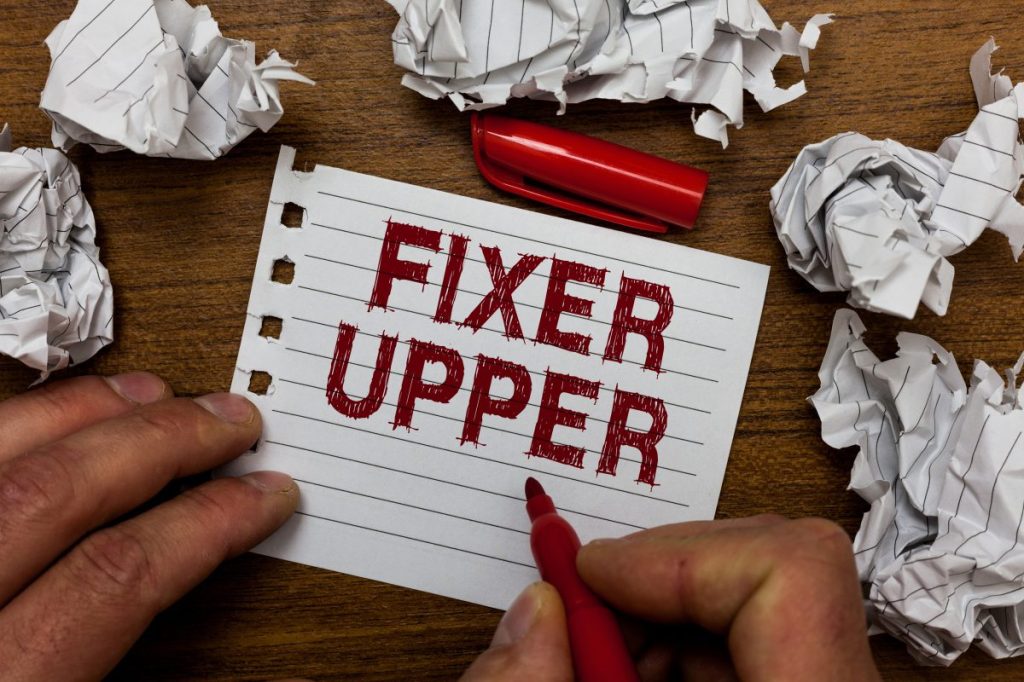 Writing note showing Fixer Upper. Business photo showcasing house in need of repairs used chiefly connection with purchase Man holding marker notebook page crumpled paper several tries mistakes.