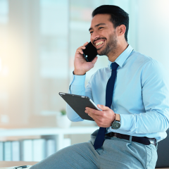 Best free real estate CRM_business man in a shirt and tie talking on his mobile phone while holding an ipad