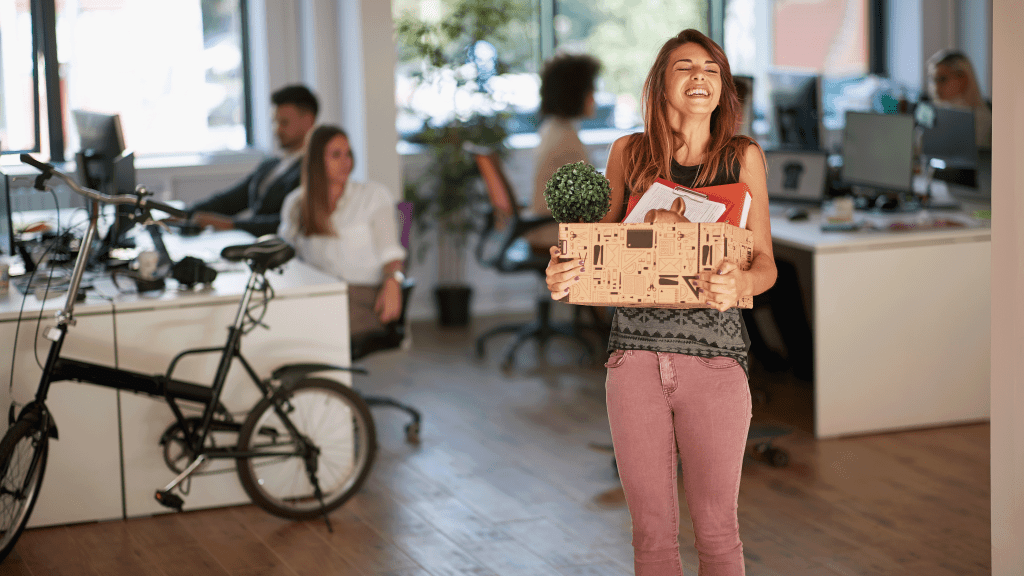 Young part-time real estate agent walks into new office with a box of belongings