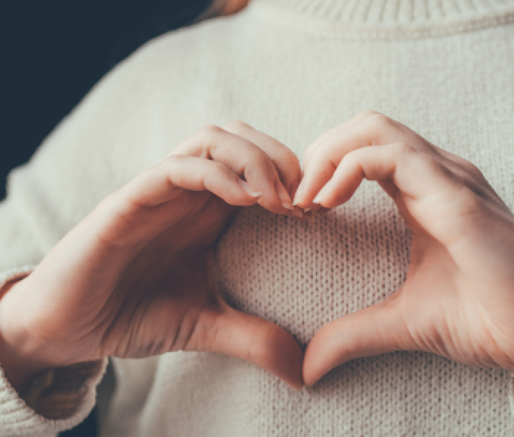 Woman's hands forming a heart over her chest