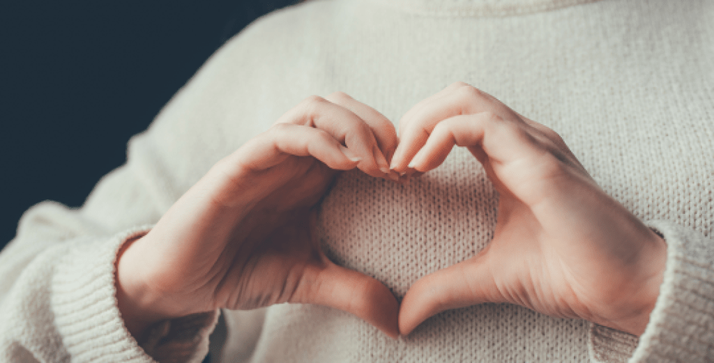 Woman's hands forming a heart over her chest