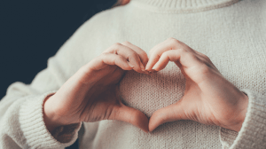 Woman's hands forming a heart over her chest